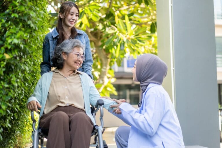 Carers assisting woman in wheelchair.